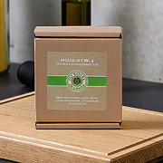 Geschlossene Originalverpackung des OLI-NATURA Pflege-Sets No. 4 auf einem geölten Schneidebrett platziert