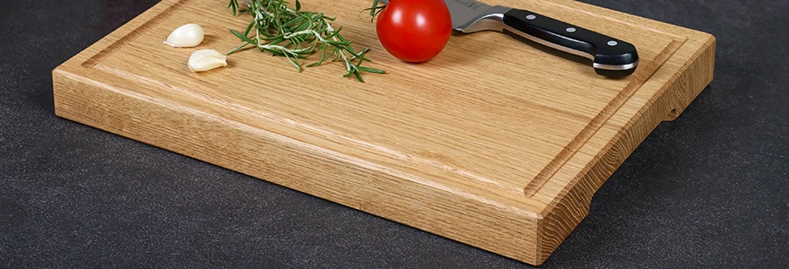 Schneidebrett aus Eichenholz mit einer Saftrille und dekoriert mit Küchenutensilien