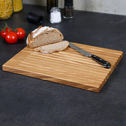 Brotschneidebrett aus massivem Eichenholz mit Brot und Messer, Seitenansicht
