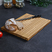 Brotschneidebrett aus Eiche mit Krümelmulden, Brotlaib und Messer auf der Arbeitsfläche