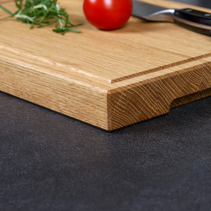 schneidebrett-eiche-handgefertigt-5 Detailaufnahme der natürlichen Holzmaserung und der elegant gefasten Kante eines handgefertigten Schneidebrettes aus Eiche - inkl. Saftrille und Griffmulde