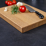 Detailaufnahme der natürlichen Holzmaserung und der elegant gefasten Kante eines handgefertigten Schneidebrettes aus Eiche