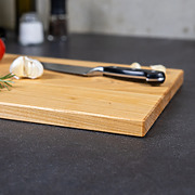 Detailaufnahme der natürlichen Holzmaserung und der elegant gefasten Kante eines handgefertigten Schneidebrettes aus Kirsche