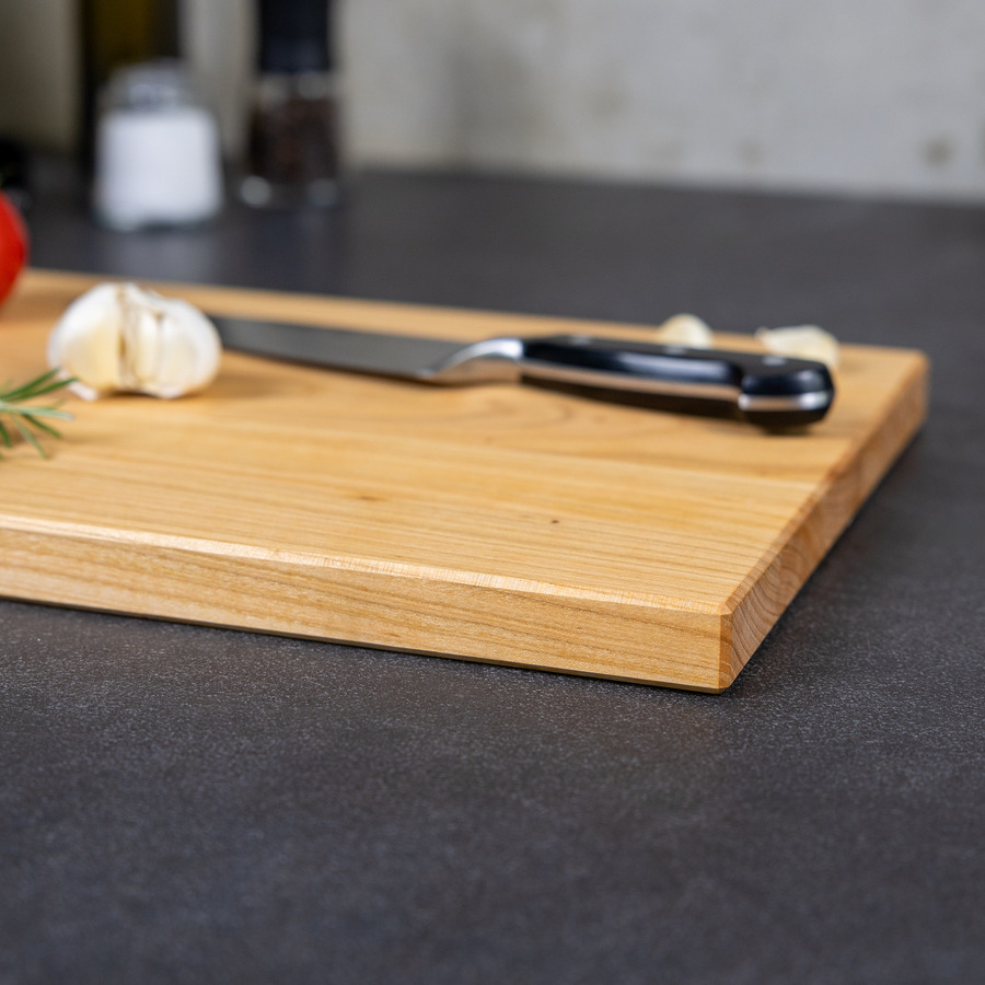 schneidebrett-kirsche-handgefertigt-4 Detailaufnahme der natürlichen Holzmaserung und der elegant gefasten Kante eines handgefertigten Schneidebrettes aus Kirsche