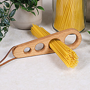 Handgefertigter Spaghettiportionierer aus Eiche mit ungekochten Spaghetti und Spaghettiglas im Hintergrund für 1-4 Personen