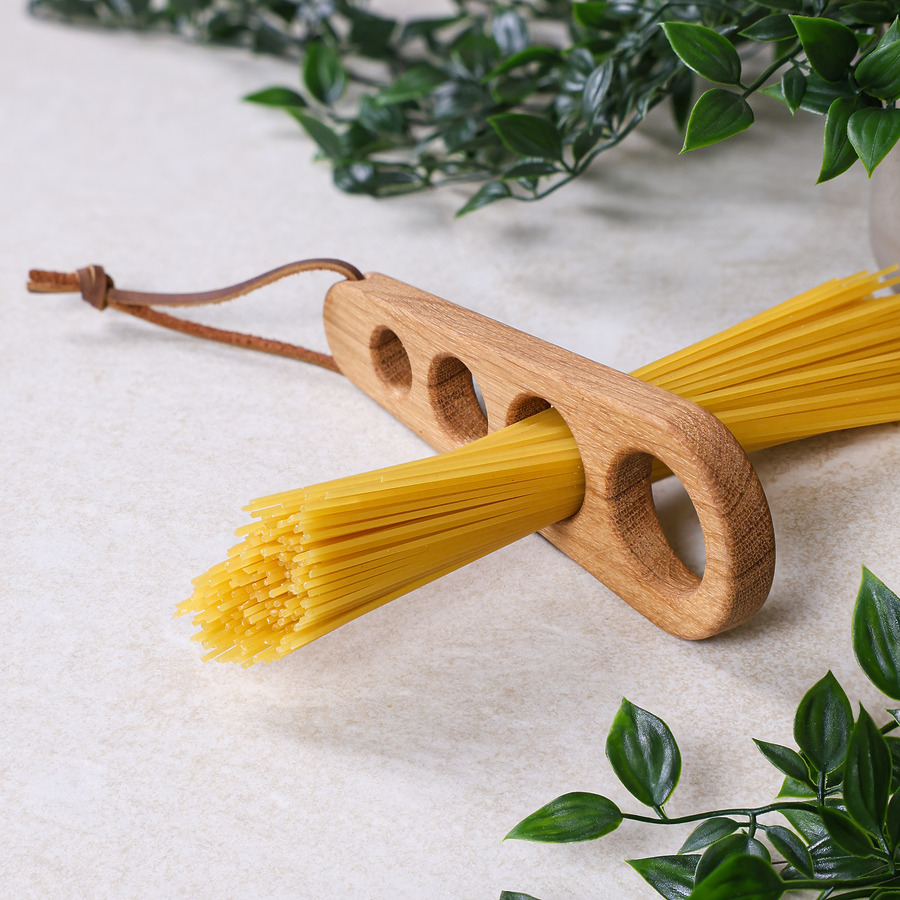 spaghettiportionierer-eiche-seitenansicht Spaghettiportionierer aus Eiche für 1–4 Personen mit Lederband, Spaghetti und dekorativem Hintergrund
